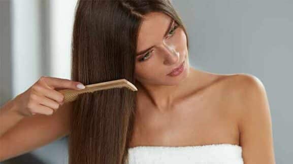 Mulher penteando cabelo com pente sobre os fios. Benefícios do café.